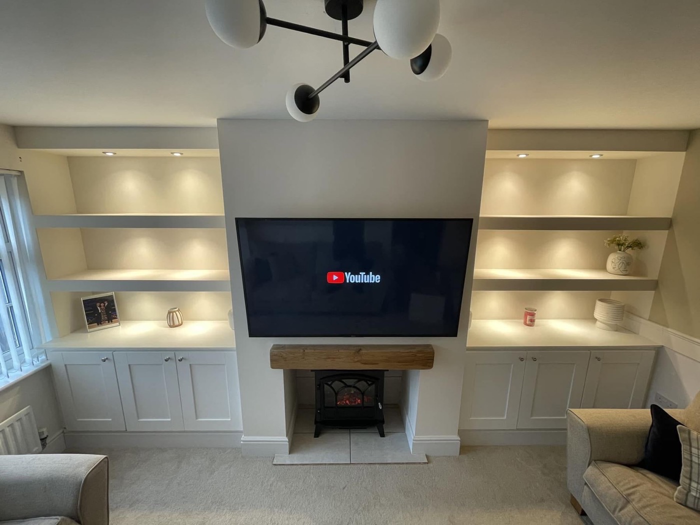 Finished media wall with lit alcove shelves and electric fire