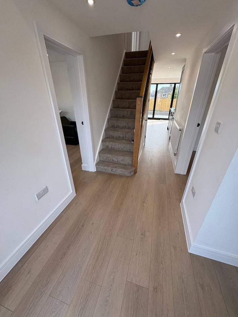 Hallway with new wood flooring, stairs and bifold doors beyond