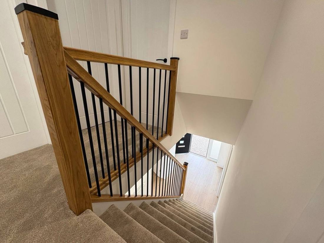 Oak staircase with black metal spindles seen from the landing