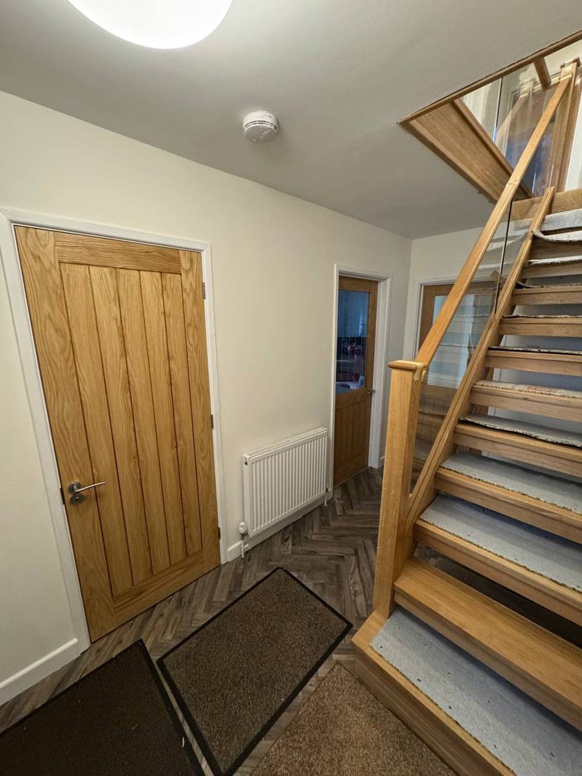 Hallway with oak door and an oak staircase with glass balustrade