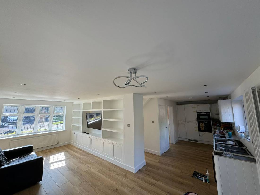 Painted fitted media unit with shelves and cupboards in an open-plan living room