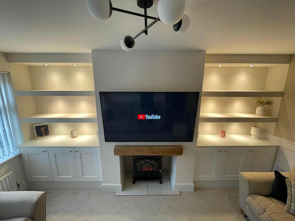 Media wall with electric fire, lit floating shelves and painted cupboards